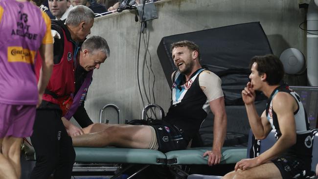 Trent McKenzie receives treatment for a knee injury on Saturday night. Picture: Darrian Traynor/AFL Photos/via Getty Images