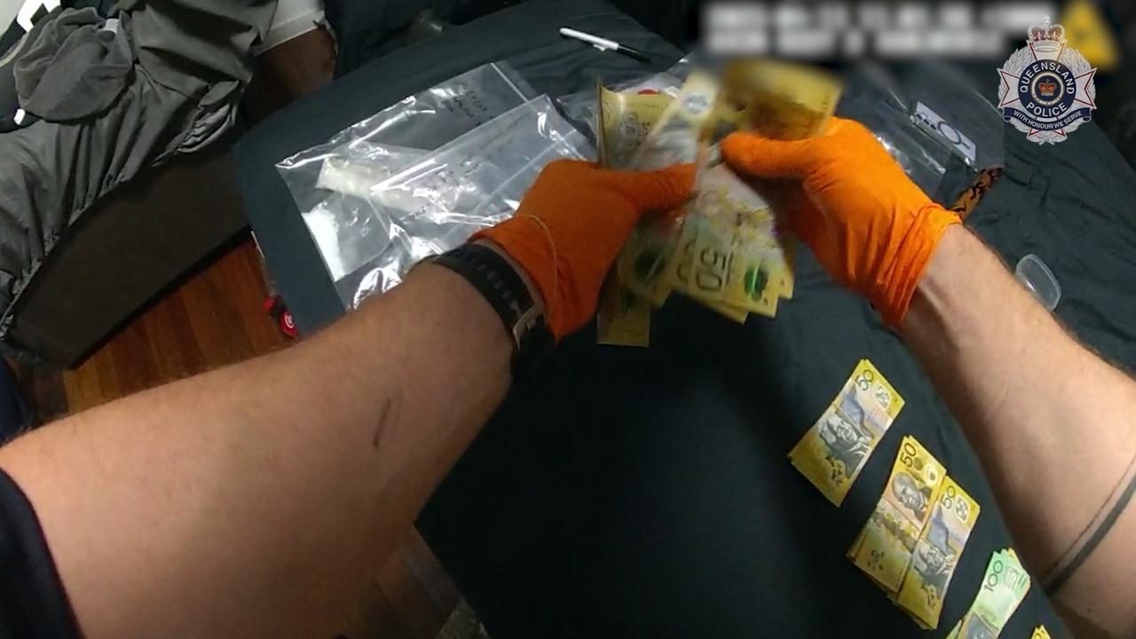 Police holding cash during alleged drug bust in Leo St, Mount Isa.