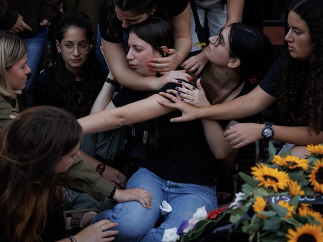 Friends console the sister of the late First Sergeant Itay Saadon, Mika, (centre) during his funeral at Misgav cemetery in Israel. Picture: Getty Images