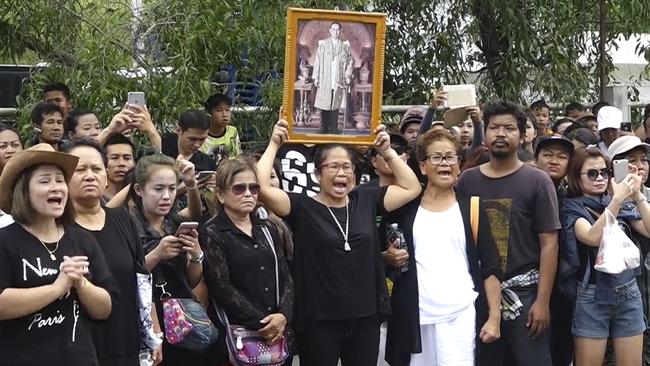 A mob shames Umaporn Sarasat as she arrives at a police station to face charges of insulting the monarch.