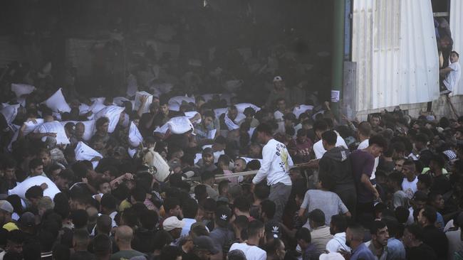 Palestinians carry bags of flour after storming a U.N. World Food Program warehouse in Zawaida, Central Gaza Strip, on Wednesday, May 28, 2025. (AP Photo/Abdel Kareem Hana)