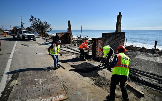 Workers on January 17, 2025 repair a road damaged by a fire that tore through the Los Angeles area