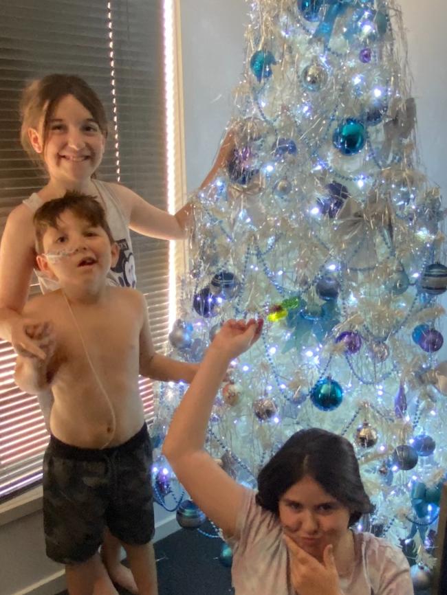 Sammy Scully, who will celebrate his last Christmas this year after doctors gave him a year to live, with his older sisters Erin and Abigail. Picture: Supplied by family