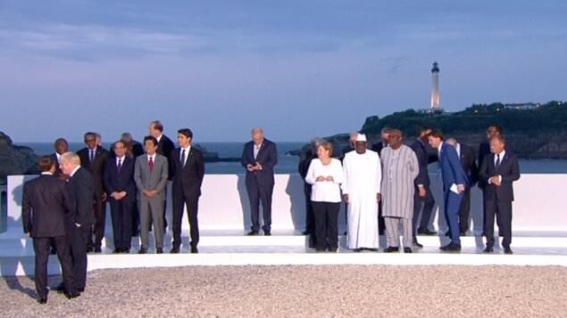 Scott Morrison looking down awkwardly at his phone during a photo op at the G7 in France.