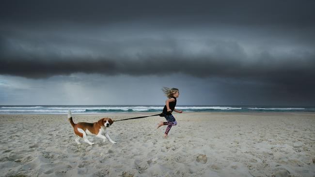 HOLD FOR Village green Ava Brewster, 7, and Walter the beagle go for a run at Mermaid Beach as rain approaches. Ava's mum is Sue - 0413753796. Pic by Luke Marsden.