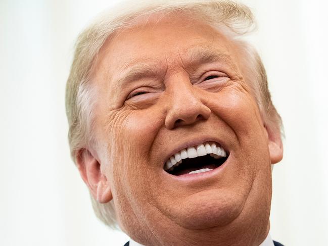 FILE:  US President Donald Trump laughs during a Medal of Freedom ceremony for Lou Holtz in the Oval Office of the White House on December 3, 2020, in Washington, DC. (Photo by Brendan Smialowski / AFP)