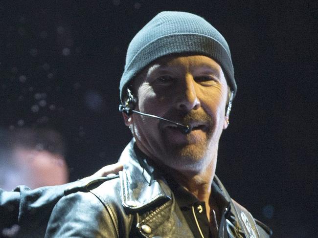 Bono, of the band U2, throws water at the crowd while the Edge watches as they perform in the band's first concert of their new world tour in Vancouver, Thursday, May, 14, 2015. (Jonathan Hayward/The Canadian Press via AP) MANDATORY CREDIT