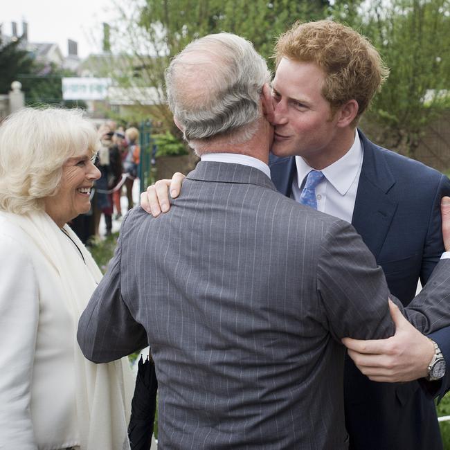 Prince Harry embraces his father Charles as Camilla smiles at the Sentebale Forget-me-not garden the Chelsea Flower Show in 2013.