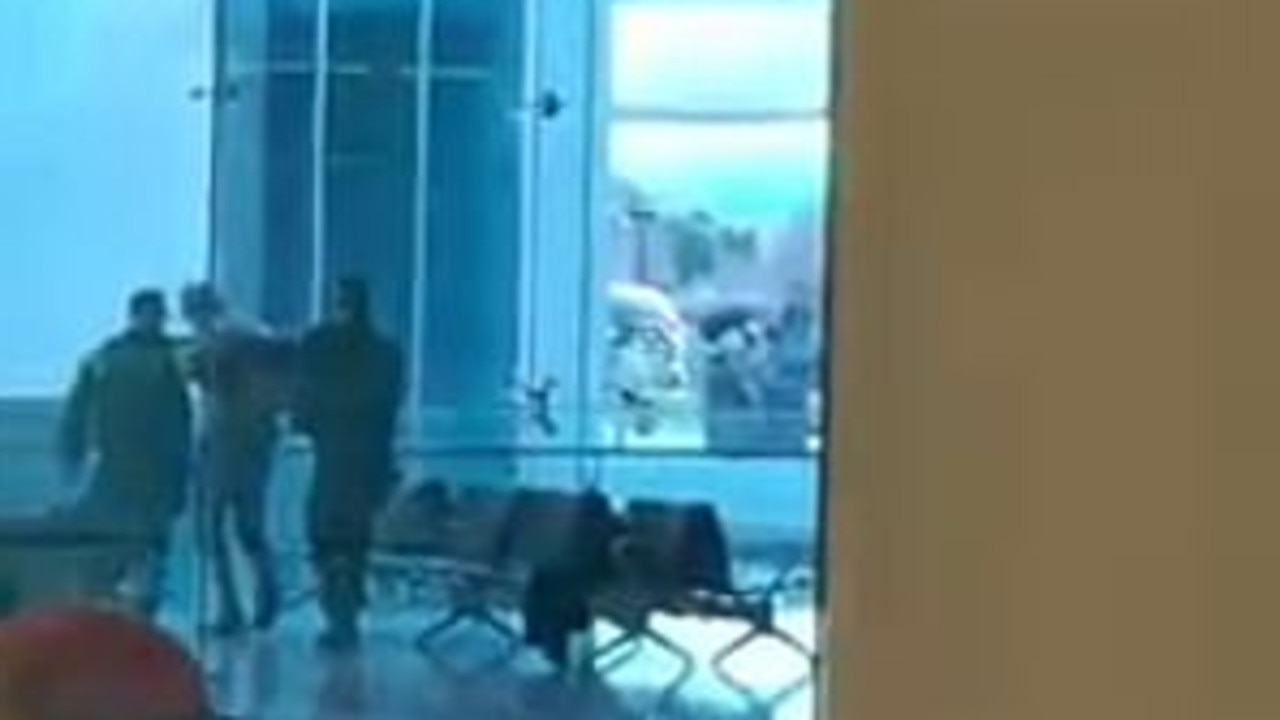 Grainy video posted to Facebook shows a man being detained by police inside the airport. Picture: Facebook