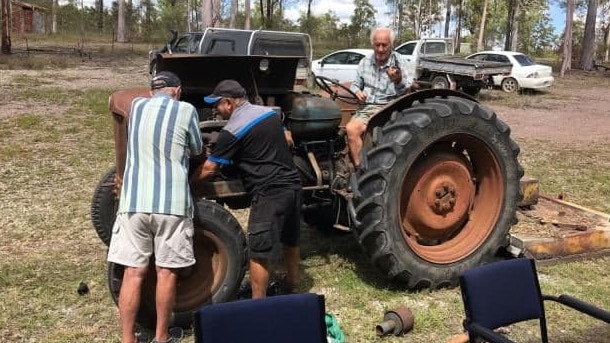 Baffle Creek Men's Shed members at work on an old tractor.