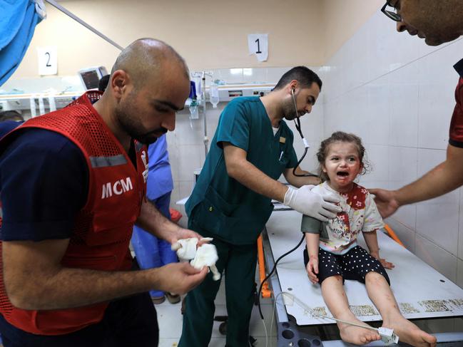 Palestinian nurse Mahmud al-Astal (L) arrives to attend to a little girl with a head wound at Nasser hospital. Picture: AFP