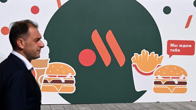 An employee stands in front of the new logo of the Russian version of a former McDonald's restaurant in June. Picture: AFP