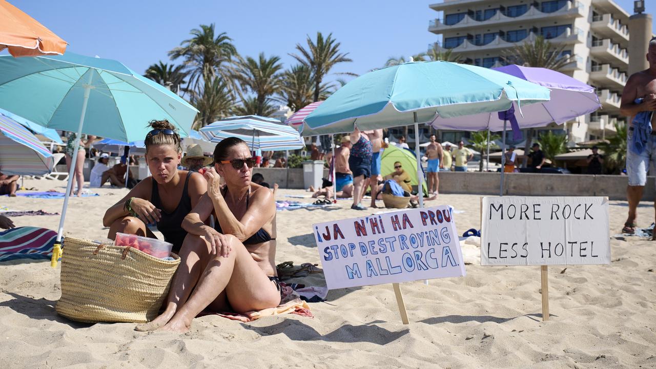 Members of the Mallorca Platja Tour association place signs against tourist saturation. Picture: Carlos Alvarez/Getty Images