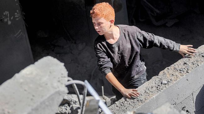 A boy climbs out from the rubble in a destroyed stairwell following Israeli bombardment of a family’s four-storey house in the north of Gaza City on Saturday. Picture: AFP