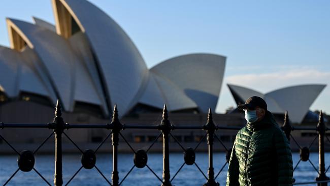 A man wears face mask as he walks along the harbour foreshore with the Sydney Opera House in the background. Picture: NCA NewsWire/Bianca De Marchi