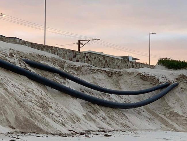 Sand pumping pipes hang precariously near West Beach Surf Lifesaving Club last week after more than a million cubic metres of sand mining has dramatically sped up dune and beach erosion. Picture: John Dundon