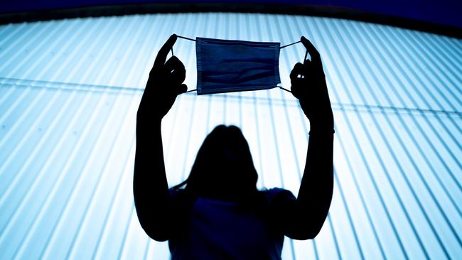 Silhouette of a Young Woman Holding Protective Face Mask in Hands Outdoors. Picture: CasarsaGuru