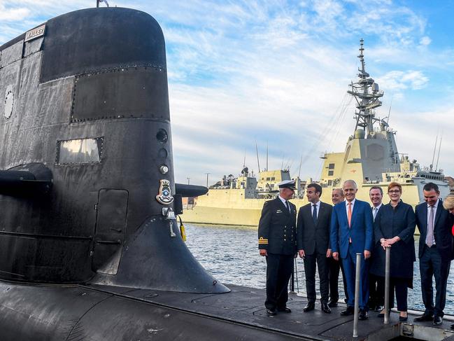 (FILES) A file photo taken on May 2, 2018 shows French President Emmanuel Macron (2/L) and Australian Prime Minister Malcolm Turnbull (C) standing on the deck of HMAS Waller, a Collins-class submarine operated by the Royal Australian Navy, at Garden Island in Sydney. - Australia is expected to scrapped a 66 billion USD deal for France to build submarines, replacing it with nuclear-powered subs using US and British technology. (Photo by BRENDAN ESPOSITO / POOL / AFP)