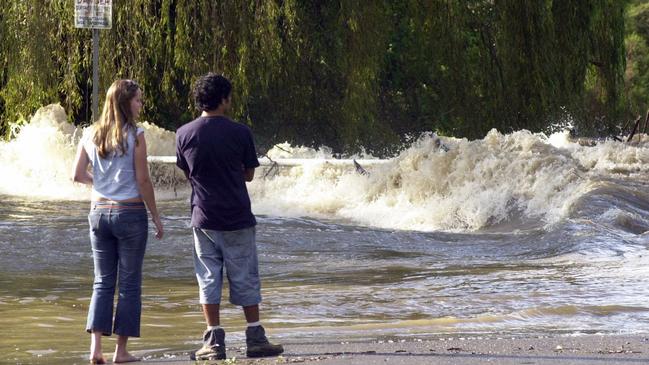 Residents watch as floodwaters races across roadway of Wakehurst Parkway after heavy rain in Ocober 2003. Picture: John Grainger