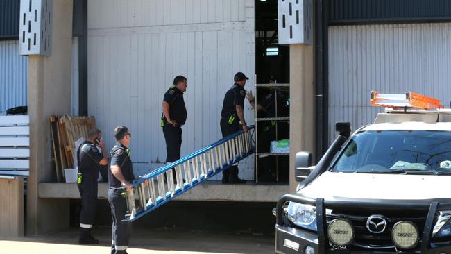 Queensland Fire Department officers enter the brewery with a ladder. Picture: Peter Carruthers