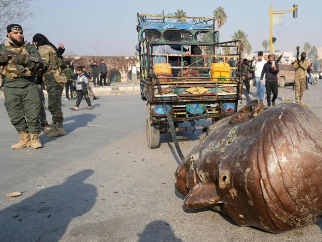 A truck pulls the head of the toppled statue of late Syrian president Hafez al-Assad through the streets of the captured central-west city of Hama. Picture: AFP