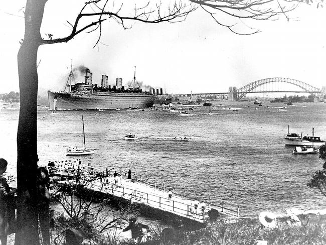 The Queen Mary, converted to carry troops to the Middle East during World War II sails out of Sydney Harbour in 1940.