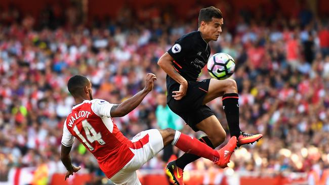 Philippe Coutinho of Liverpool is challenged by Theo Walcott.