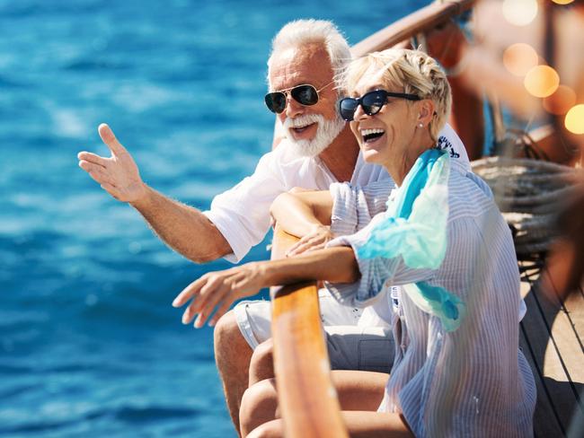 Closeup side view of mid 60's couple enjoying a sailing cruise during summer vacation at seaside.