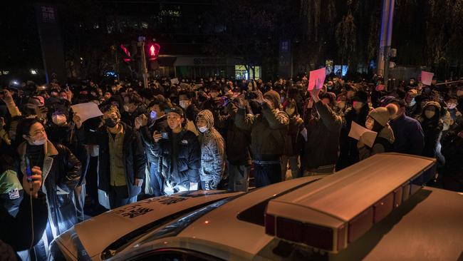 Protesters march by a police cruiser during a protest in Beijing, China. Picture: Kevin Frayer/Getty Images