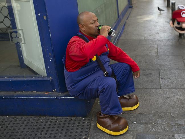 A man wearing a Mario Bros costume takes a break from work posing for tourist photos in the shade at Sol square in Madrid. Picture: Francisco Seco