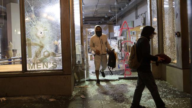 Looters emerge with merchandise from an Urban Outfitters store in Seattle, Washington. Picture: AFP