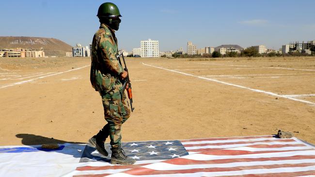 A Yemeni Huthi fighter walks on the flags of Israel and the US during a rally the Iran-backed group held in Sanaa.