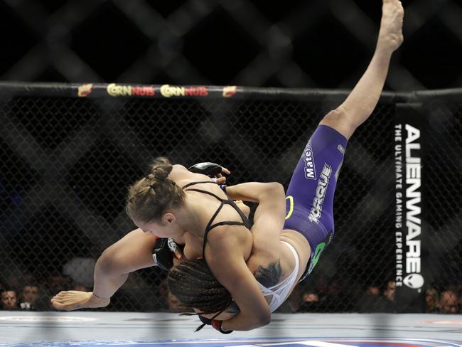 Ronda Rousey, left, takes down Alexis Davis during their women's mixed martial arts bantamweight title bout at UFC 175 in Las Vegas.