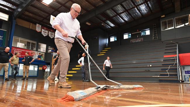 He may not ‘hold the hose, mate’ but Scott Morrison was quick to pick up a mop in on Thursday to help dry a flood damaged court at the Brisbane Basketball Court. Picture: AAP