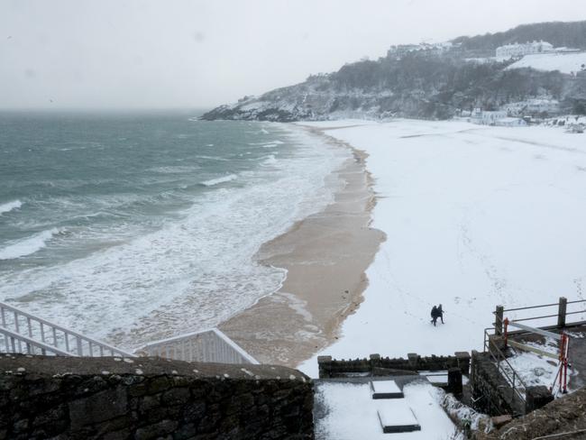 People walk on the snow covering the sand at Carbis Bay as snow arrives in St Ives on February 28, 2018 in Cornwall, England. Freezing weather conditions dubbed the “Beast from the East” has brought snow and sub-zero temperatures to many parts of the UK. Picture: Getty Images