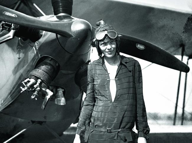 Earhart stands in front of her plane.