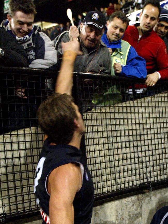 A Collingwood fan taunts Corey McKernan with a wooden spoon in 2002.