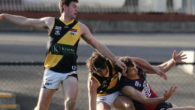 Kyneton’s Darcy Harris and Rhys Magin grapple with Sandhurst’s Matthew Thornton. Picture Yuri Kouzmin