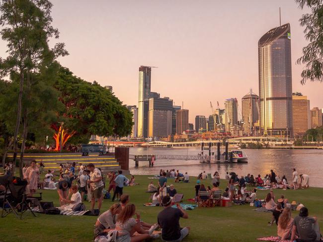 Picnics on Riverside Green in South Bank, a recreational area in Brisbane, Australia, likely host of the 2032 Olympic Games. South Bank looks across the Brisbane River to the city skyline.Escape 23 April 202348 Hours BrisbanePhoto - iStock