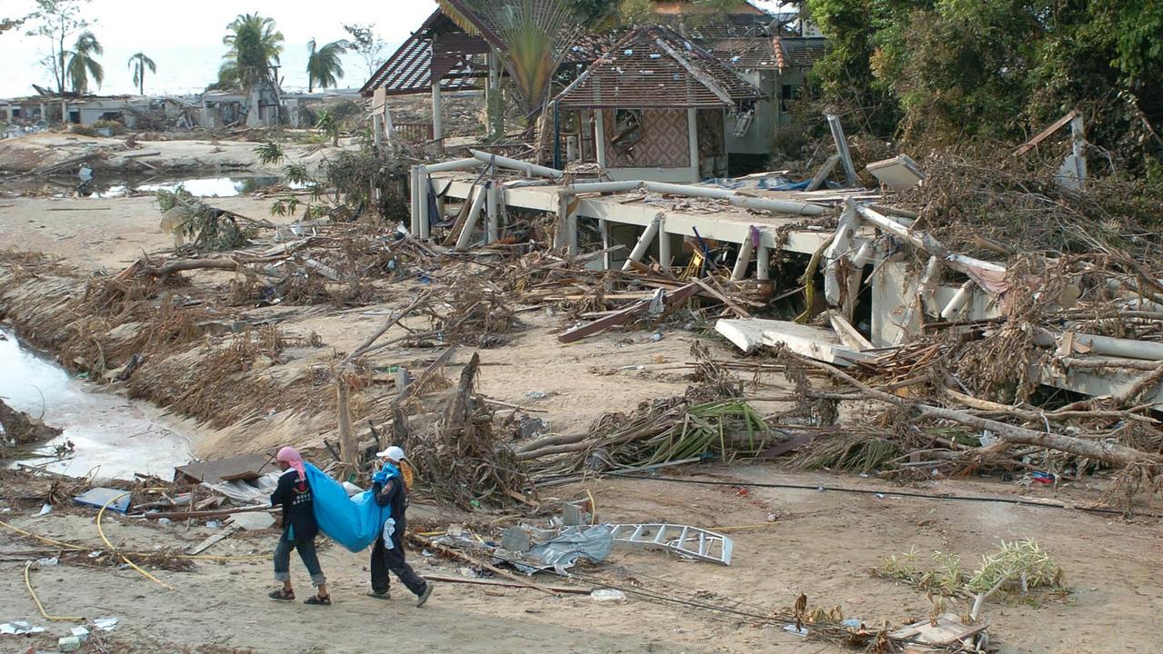 Two Thai rescuers carry a body recovered from the destroyed Khao Lak Laguna Resort Hotel following the 2004 Indian Ocean tsunami. Picture: Romeo Cacad / AFP