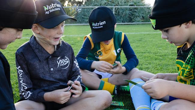 Children play with Kate's custom made cards that represent their team. Picture: Claire Martin