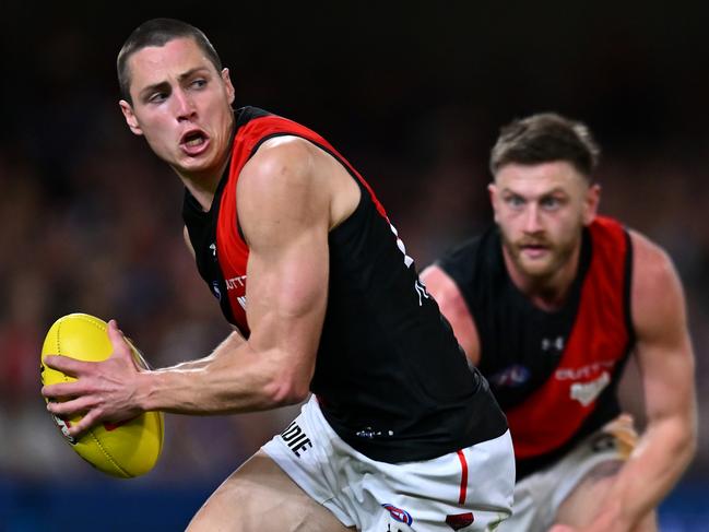 BRISBANE, AUSTRALIA - AUGUST 24: Jake Kelly of the Bombers handles the ball during the round 24 AFL match between Brisbane Lions and Essendon Bombers at The Gabba, on August 24, 2024, in Brisbane, Australia. (Photo by Albert Perez/Getty Images)