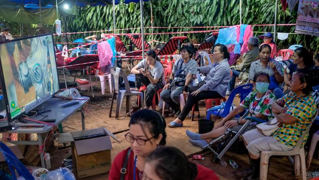 Family members watch news about rescue operation at a makeshift camp at Khun Nam Nang Non Forest Park.