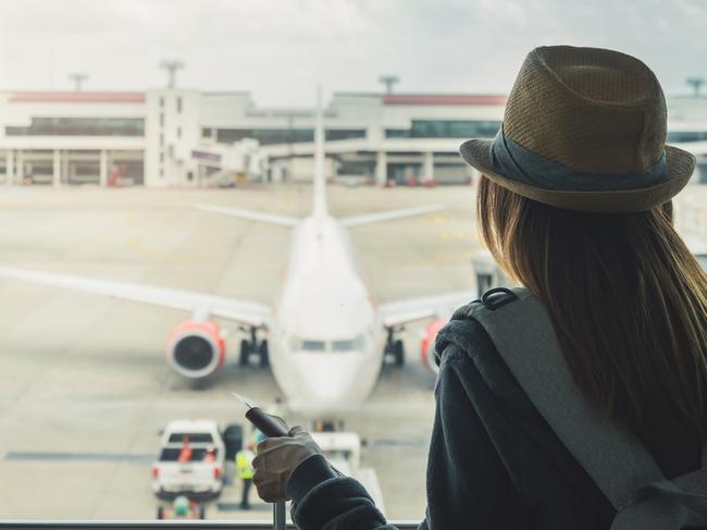 ESCAPE:  Young woman traveler with luggage holding passport looking at the airplane at the airport, Travel concept  Picture: Istock