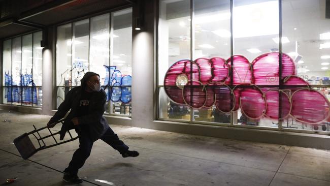 A man throws a hand truck into the window of vandalised CVS store during a protest in Los Angeles over the death of George Floyd. Picture: AP