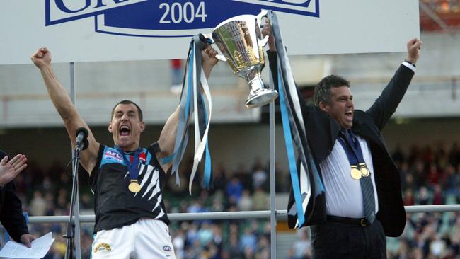  Warren Tredrea and Mark Williams with the premiership cup after winning the 2004 Grand Final. The club’s creed says it “exists to win premierships”.