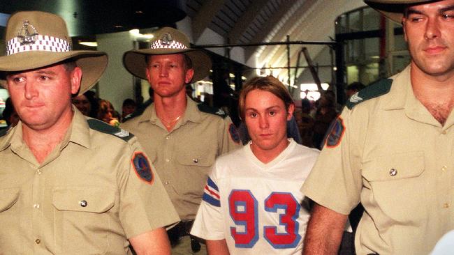 Ben William McLean is escorted through Darwin Airport.