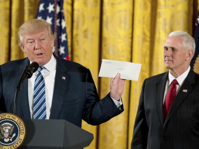 President Donald Trump, accompanied by Vice President Mike Pence, right, holds up a letter left for him by former President Barack Obama as he speaks at a White House senior staff swearing in ceremony in the East Room of the White House, Sunday, Jan. 22, 2017, in Washington. (AP Photo/Andrew Harnik)