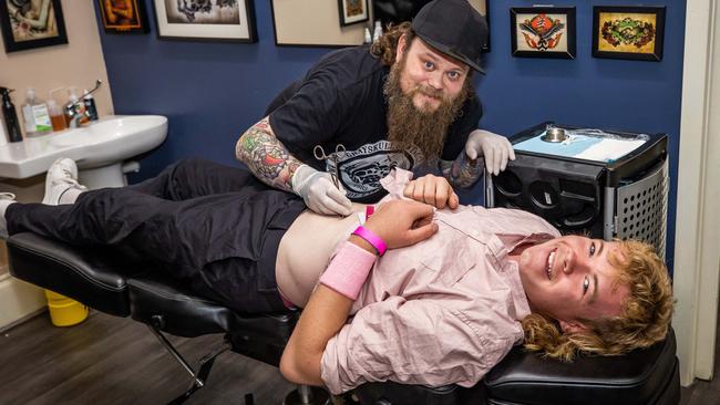 Callum Levi getting a belly button ring from head body piercer and manager at Victor Tattoo and Body Piercing Chris Causby. Picture: Tom Huntley