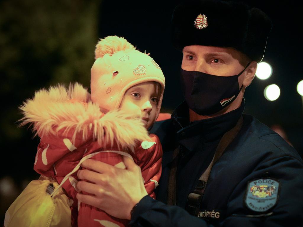 A Hungarian police officer carries a refugee child across the dark tracks at Zahony train station as the influx of refugees from Ukraine continues through the night in Zahony, Hungary. Picture: Getty Images